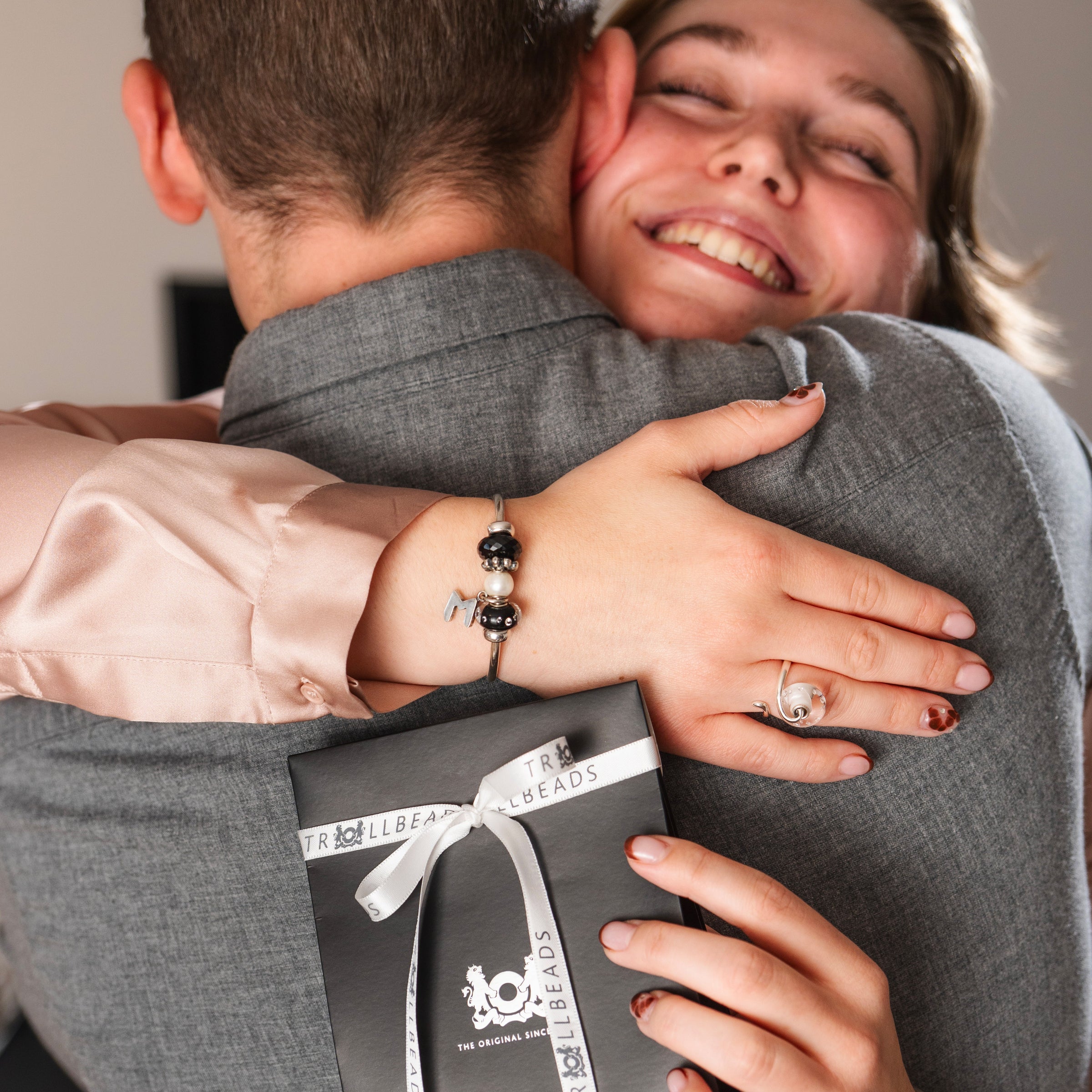Couple hugging each other in a gift giving moment with Trollbeads gift bag and jewellery